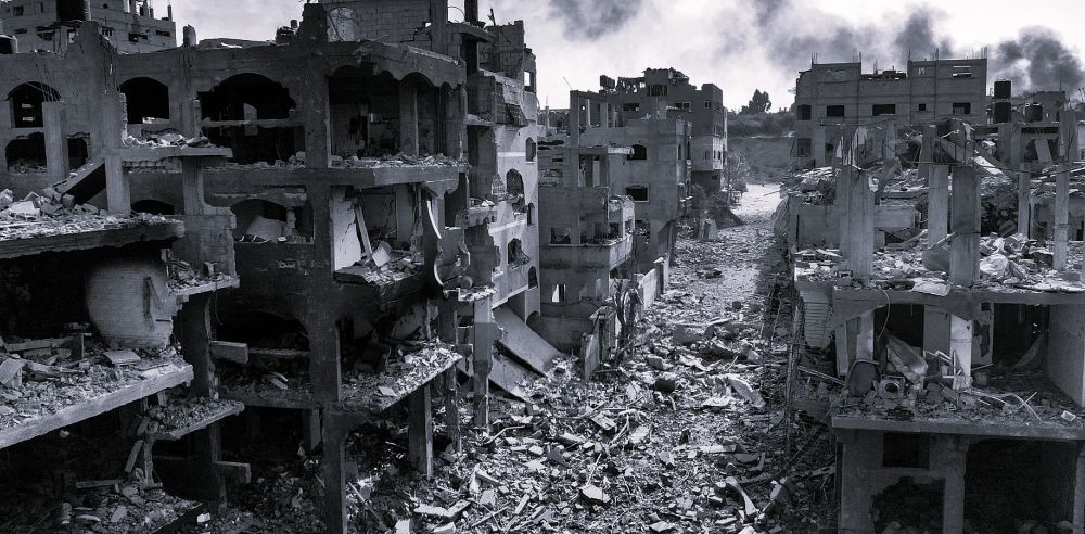 Black-and-white photo of destroyed buildings and a debris-covered street in Gaza, 2024.